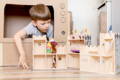 Little boy playing in a cardboard DIY castle.