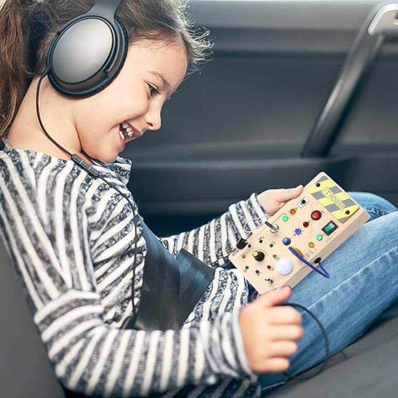 Little girl playing with Montessori Wooden Sensory Board in the back of the car while traveling.