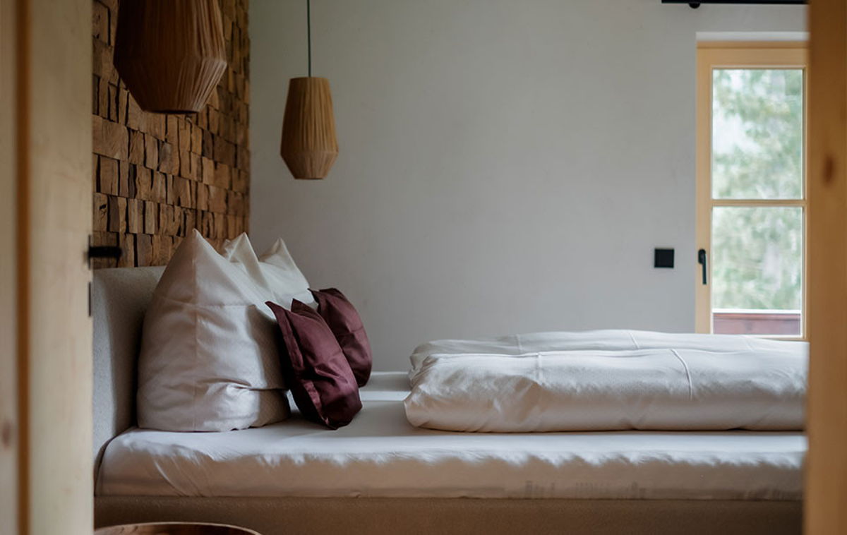 Schlafbereich mit Doppelbett und Holzpaneelwand im Apartment Vogelfrei von Hugo & Pepi.