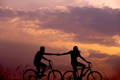 Silhouette d'un couple sur velos devant le ciel rose