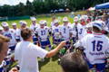 Lacrosse players in uniform during a timeout gathered around coach going over next play.