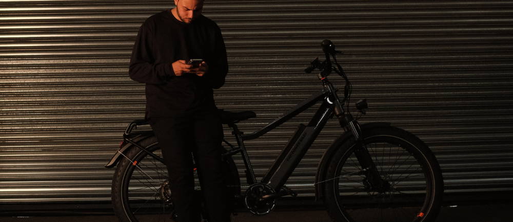A guy standing next to his ebike looking at his phone