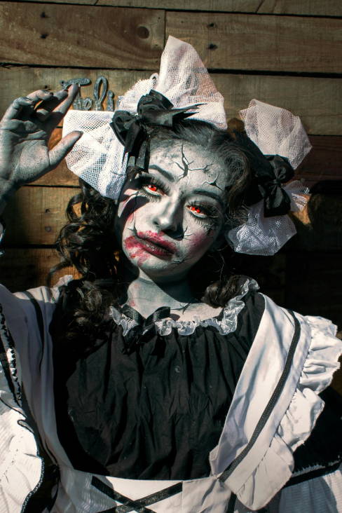 woman dressed as a creepy doll with cracked poreclain skin