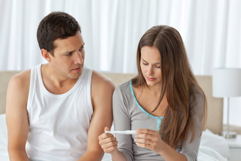 Couple sadly looking at a negative pregnancy test