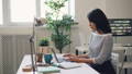 Femme travaille dans un bureau moderne avec un ordinateur portable, une lampe et une plante