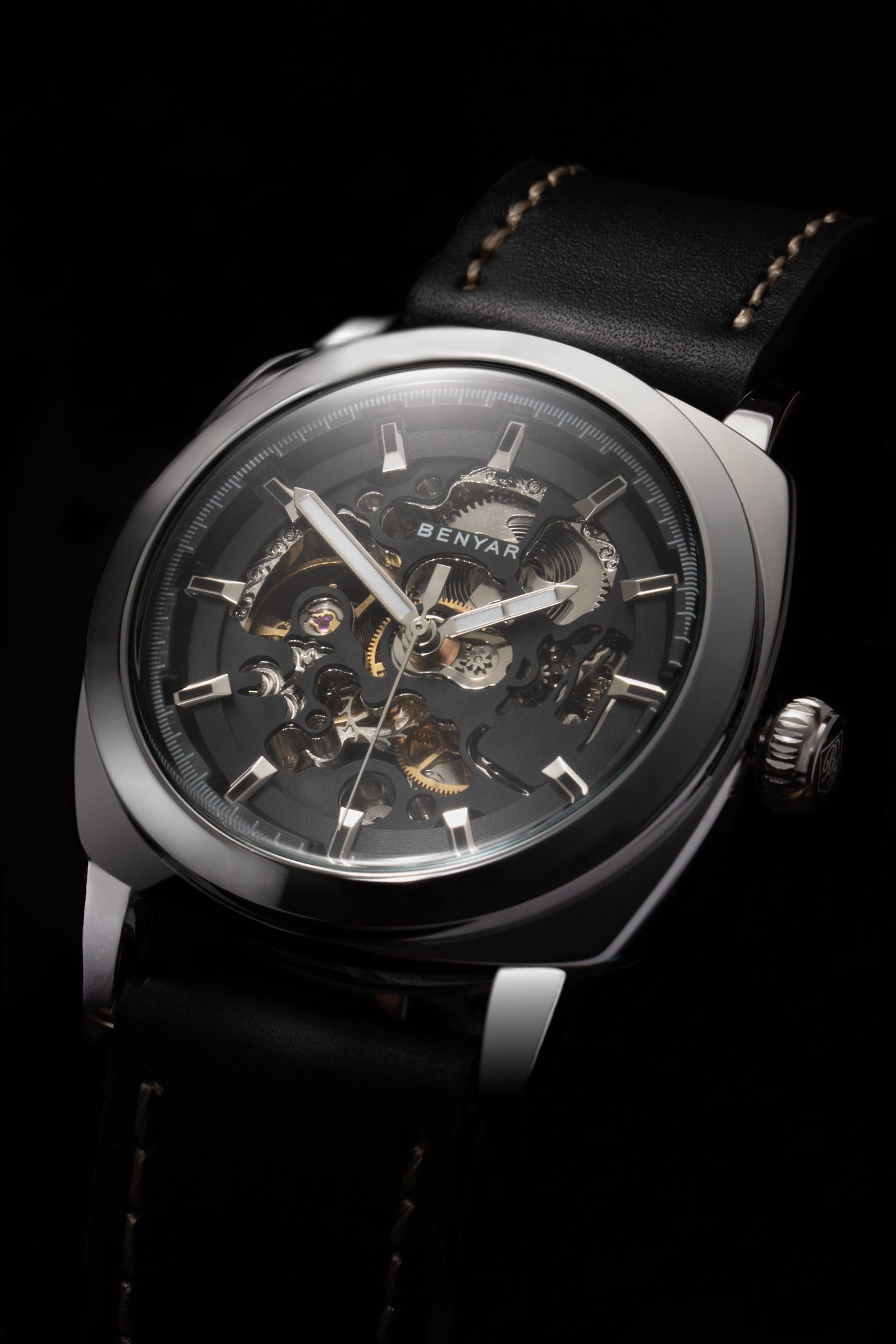 Close-up of a BENYAR skeleton watch on a black background. The watch has a gold-colored case and a black leather strap