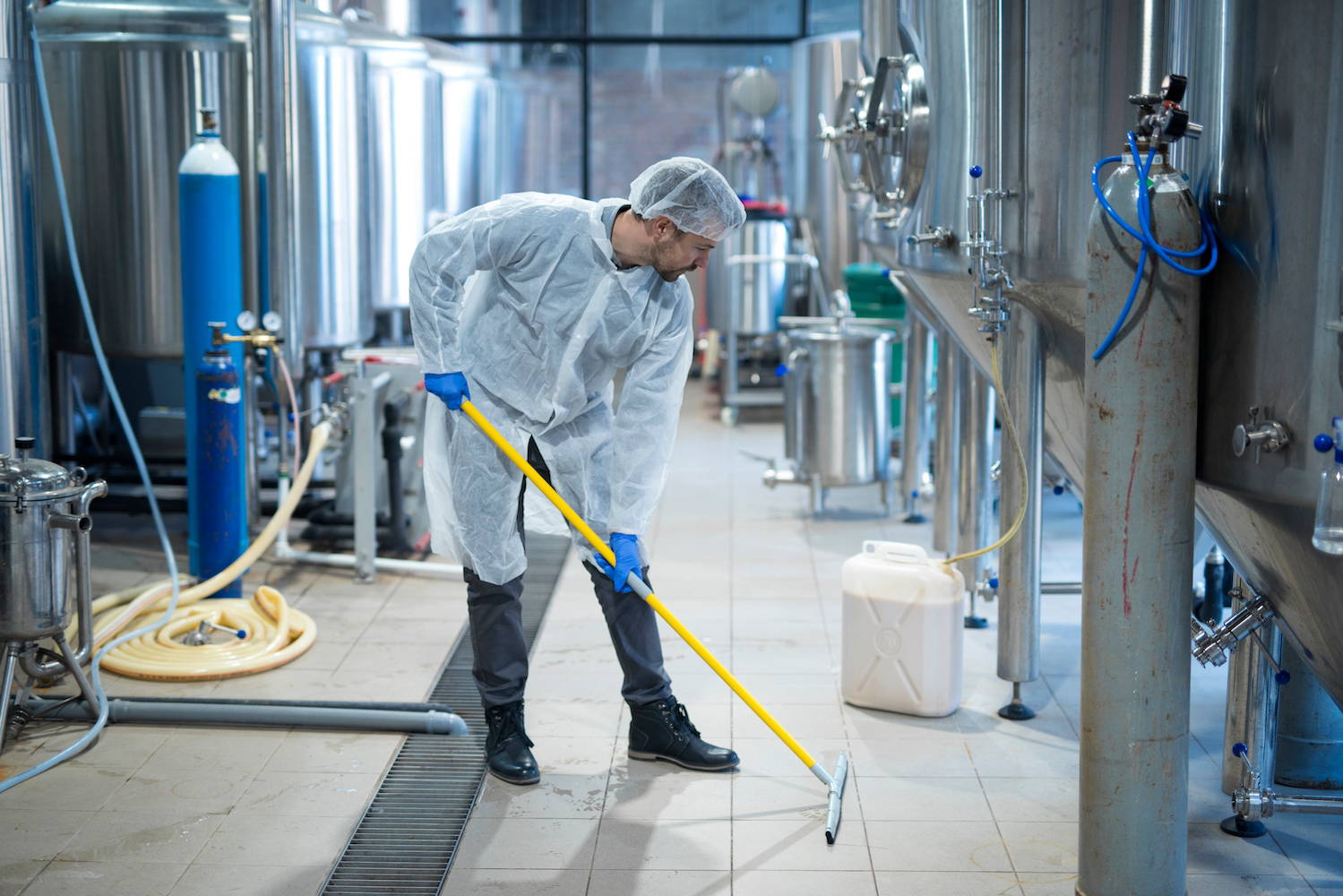 Man cleaning a manufacturing plant floor as part of hygiene procédures
