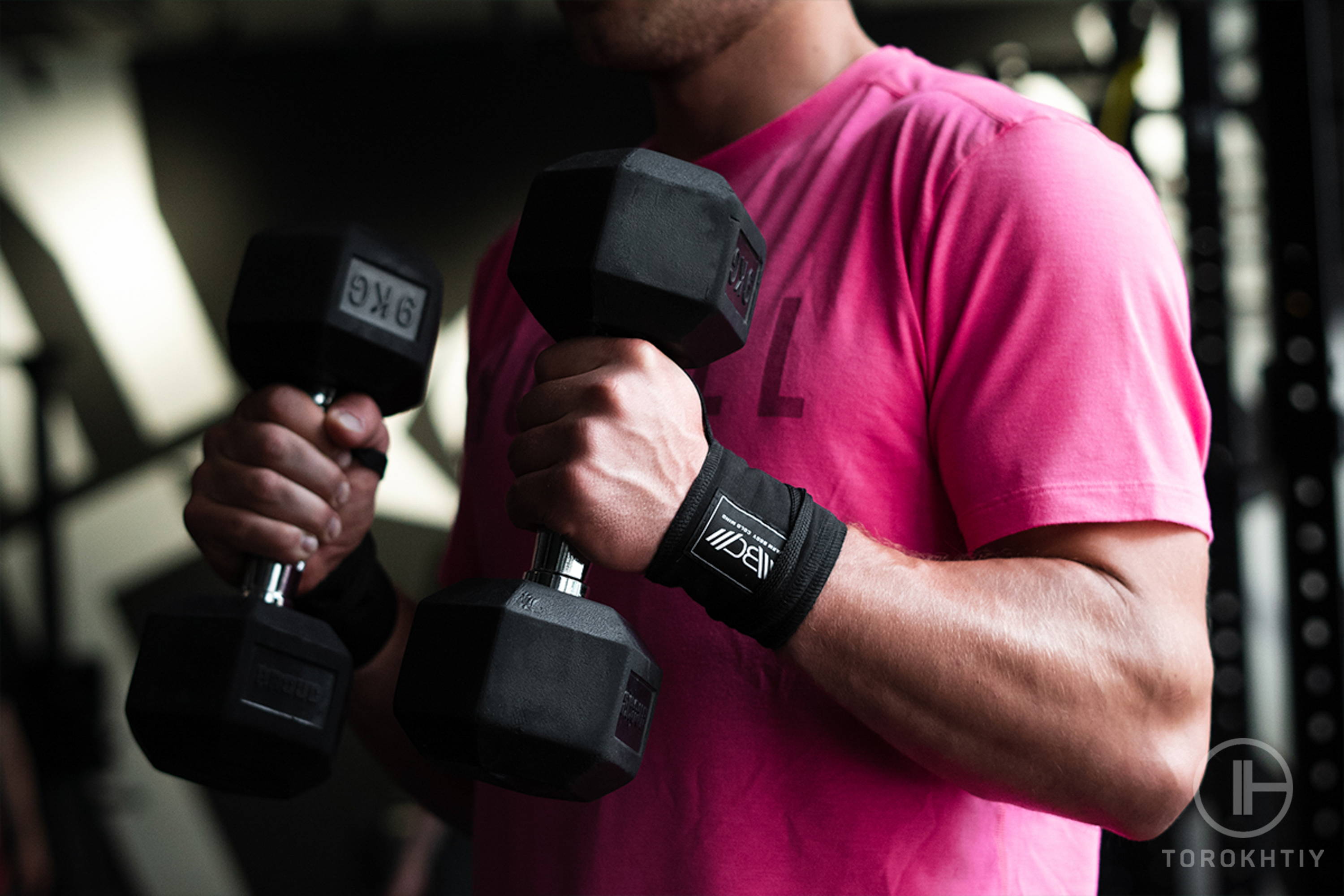 athlete in pink shirt training with dumbbells