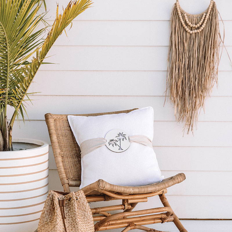 Palm tree cushions featuring on a rattan chair to create a coastal home