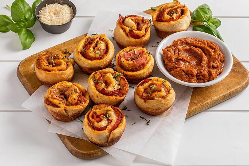 Cutting board with pizza rolls and marinara sauce.