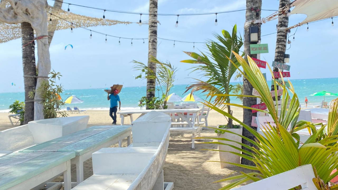 white picnic tables and green palm trees on white sand beach overlooking blue ocean at Kite Beach Dominican Republic