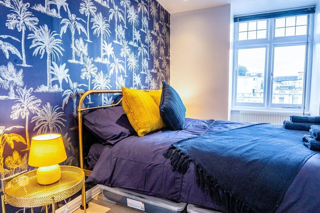 Bedroom with blue bed sheets and yellow pillows