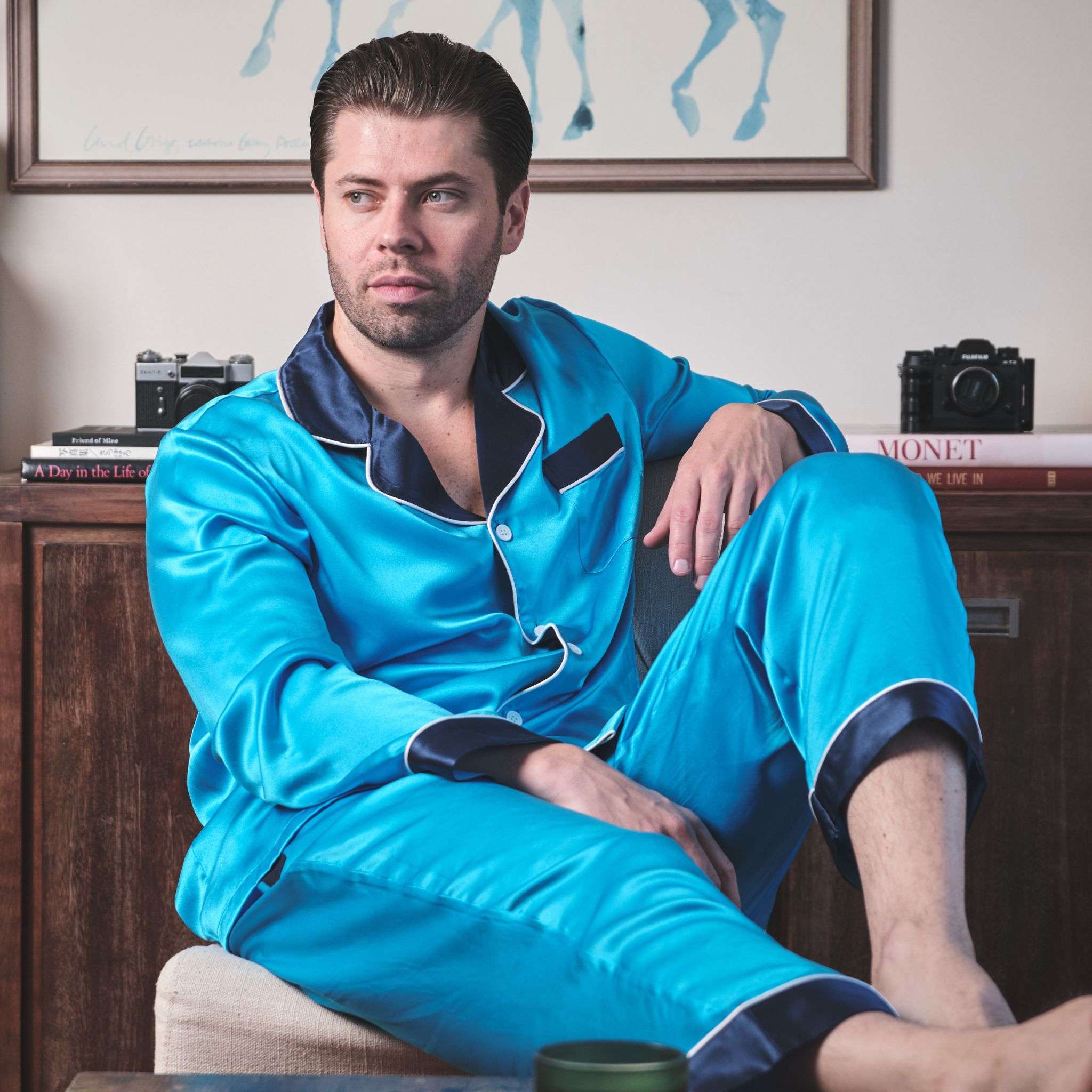 photo of a model sitting in a chair while wearing a blue silk pajama set