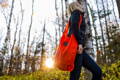 woman carrying a hunter orange urban foraging tote in the woods