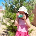 Little girl holding a Montessori Wooden Camera and pretending to take a photo. 