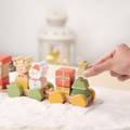 Woman's hand interacting with the Montessori Xmas Brain Train by stacking a final wooden piece onto a train cart.