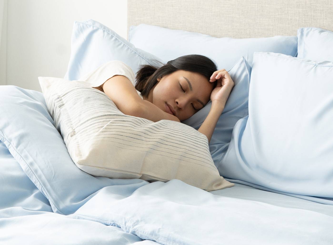 Woman sleeping on Weavve's sky blue cooling bed sheets
