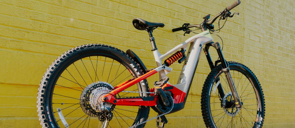 a Cannondale Moterra Neo Worth full suspension electric mountain bike in front of a yellow brick wall