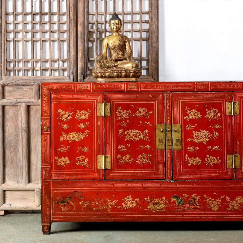 An antique Chinese red lacquer Dongbei sideboard with a reproduction Buddha statue