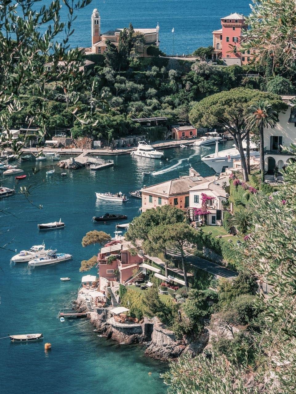 The Jewel by Stuart Cantor - A photograph of the seaside village of Portofino from above, with speedboats travelling through the deep blue water and terracotta old buildings perched on cliff edges.