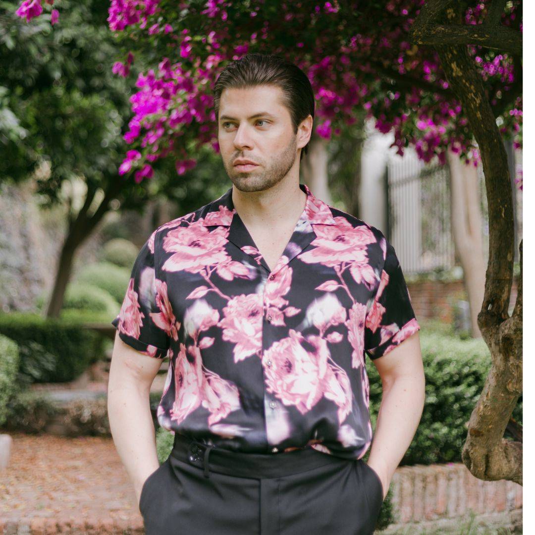 model standing in the garden and wearing a black floral short sleeve silk shirt from 1000 kingdoms