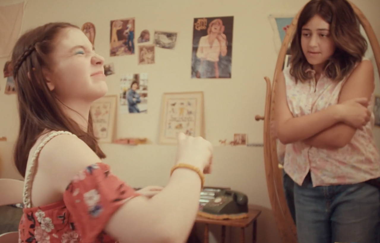 Two teenage girls; one spraying on her Love's Baby Soft cologne.