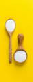 Two spoons full of collagen powder on yellow background