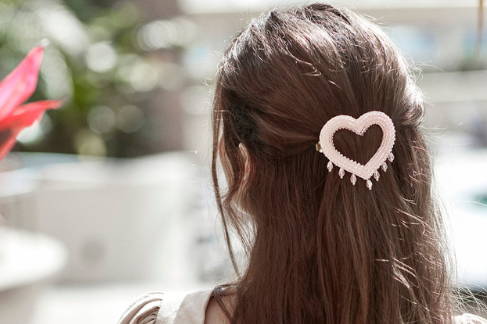 Lady wearing the CORA rosé crystal heart shaped  hair barrette with a halfup-half down hair do.