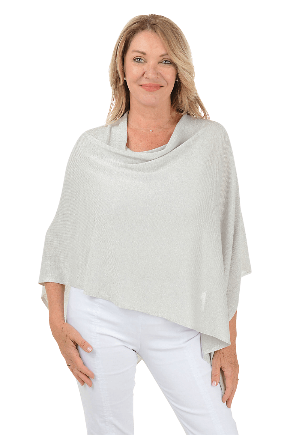 A woman wearing a glittery silver poncho and white pants against a beige background