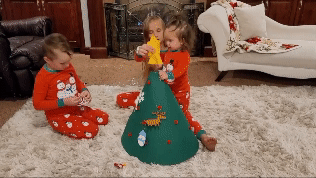 Stop motion showing ornaments being put on the Christmas Tree by children. 