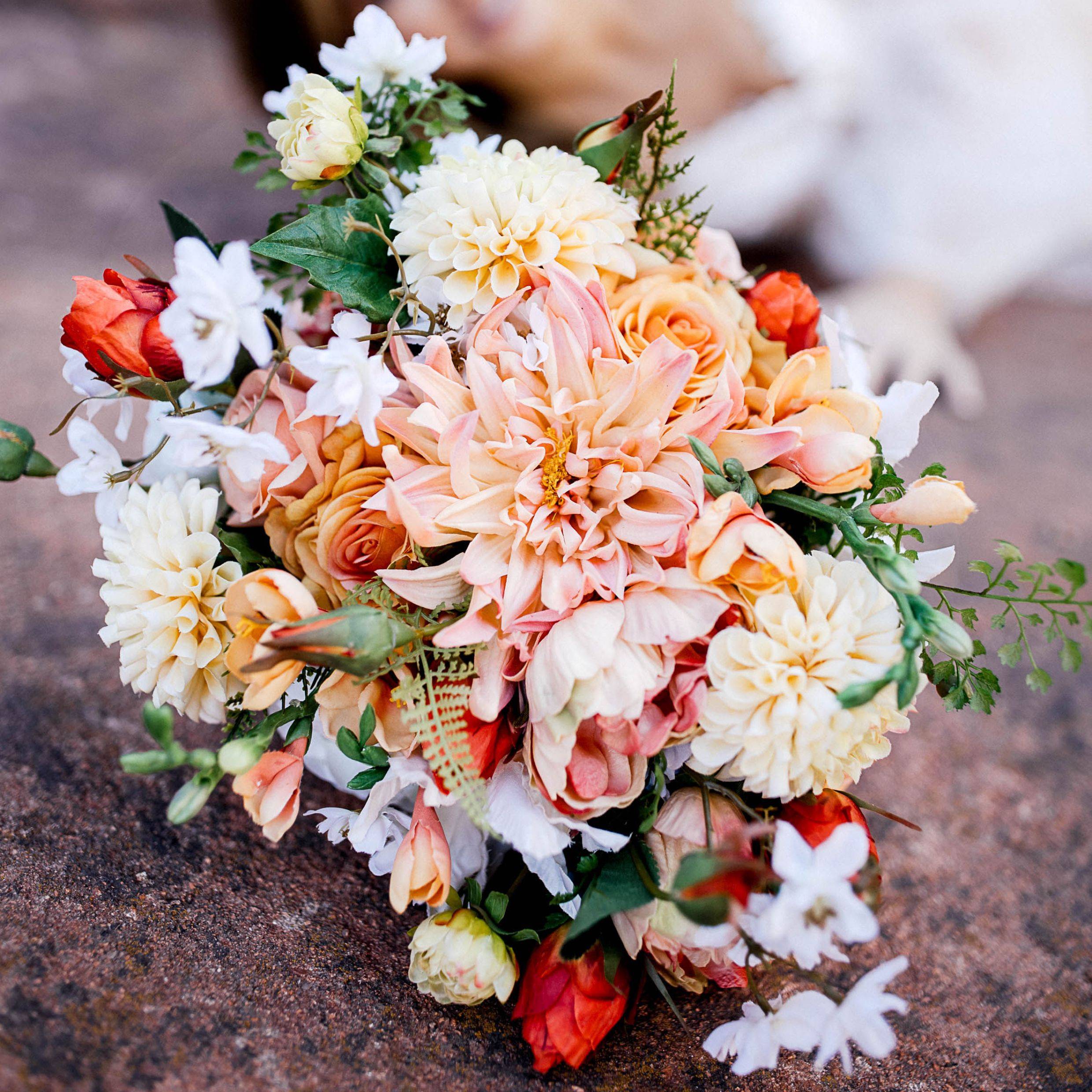 Bright summery bridal bouquet with a pink dahlia, cherry blossoms, and orange roses 