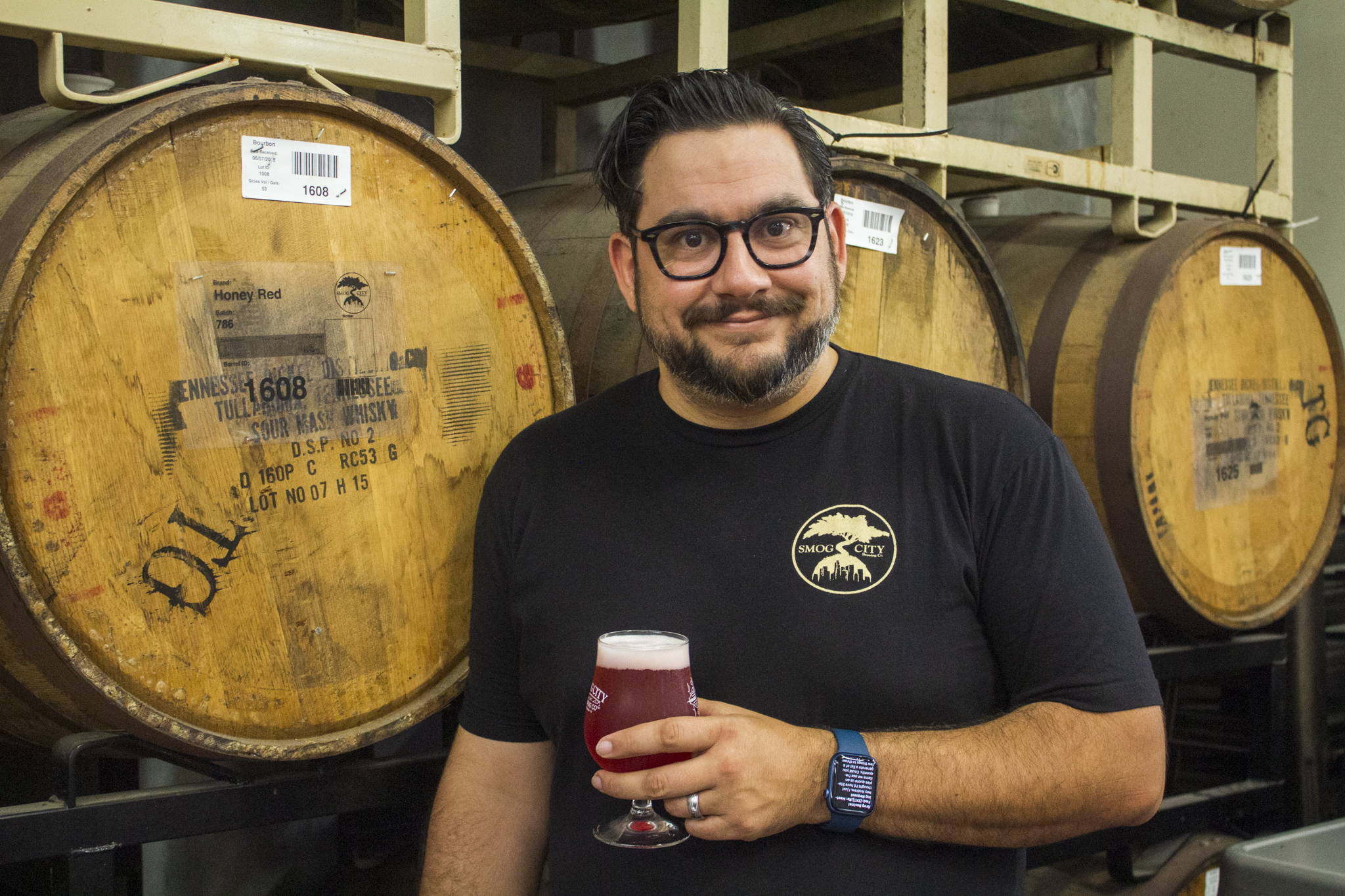 Lead Brewer Jake is smiling with his brew glasses around his neck.