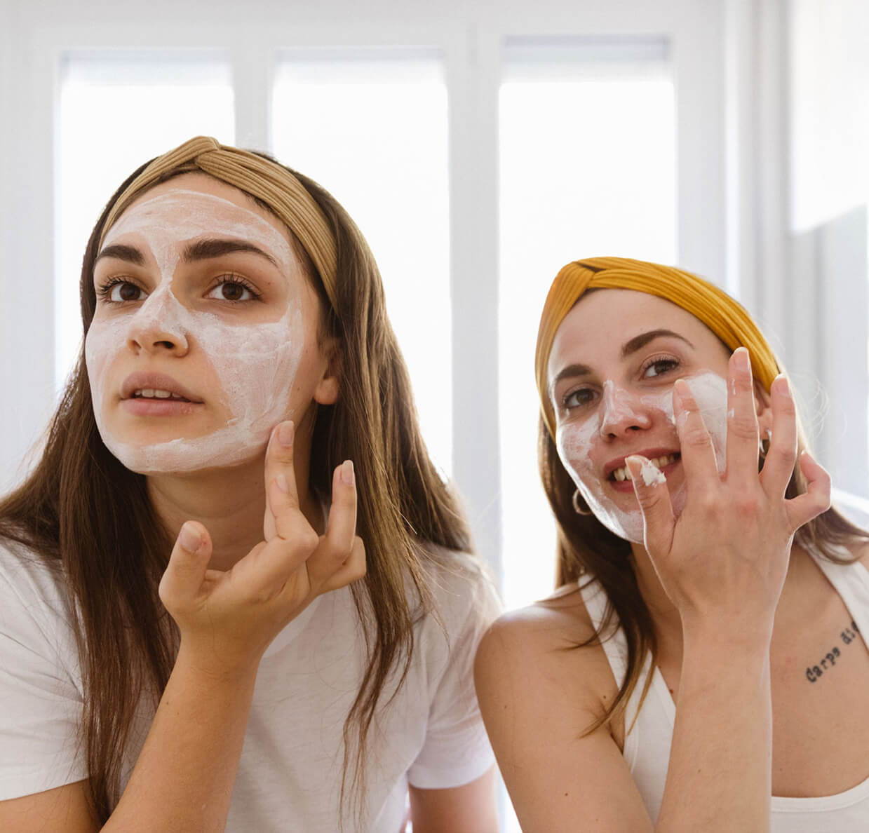 2 women applying skin care on their face