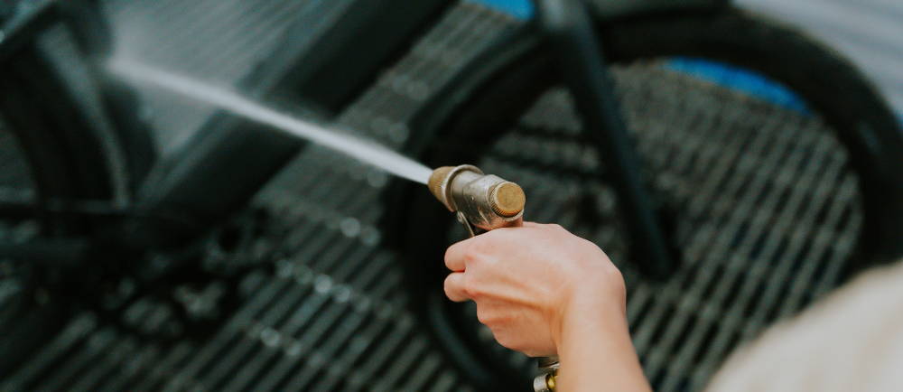 Person spraying an electric bike with a water hose