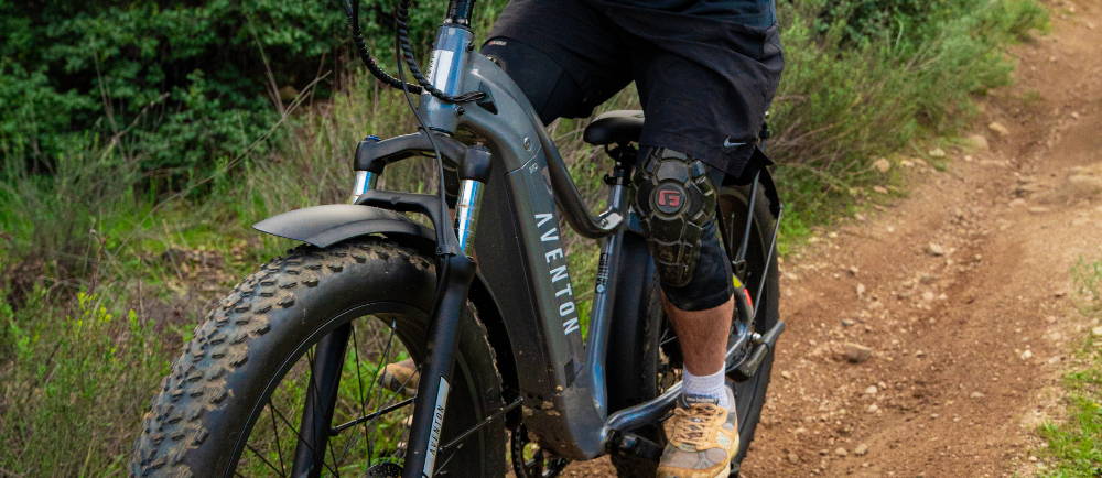 A man riding a green Aventon Aventure fat tire electric bike