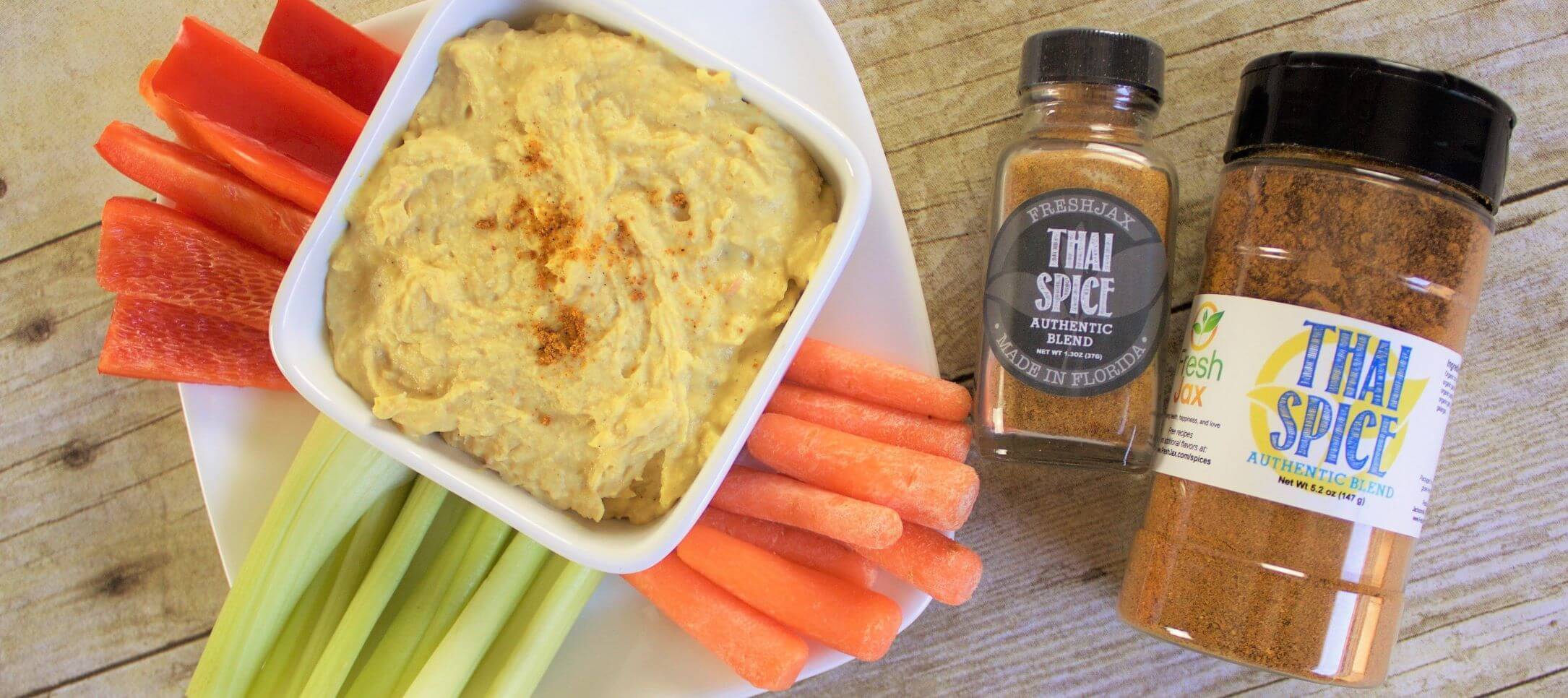 FreshJax Organic Thai Spice white bean hummus with a veggie plate of carrots, red bell peppers, and celery 