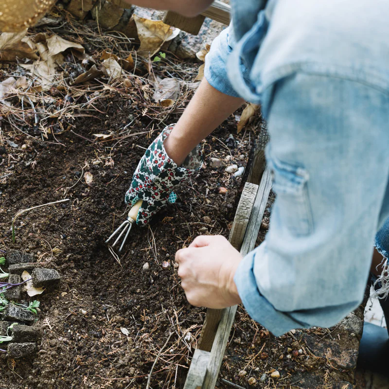 Woman digging down into a raised garden bed