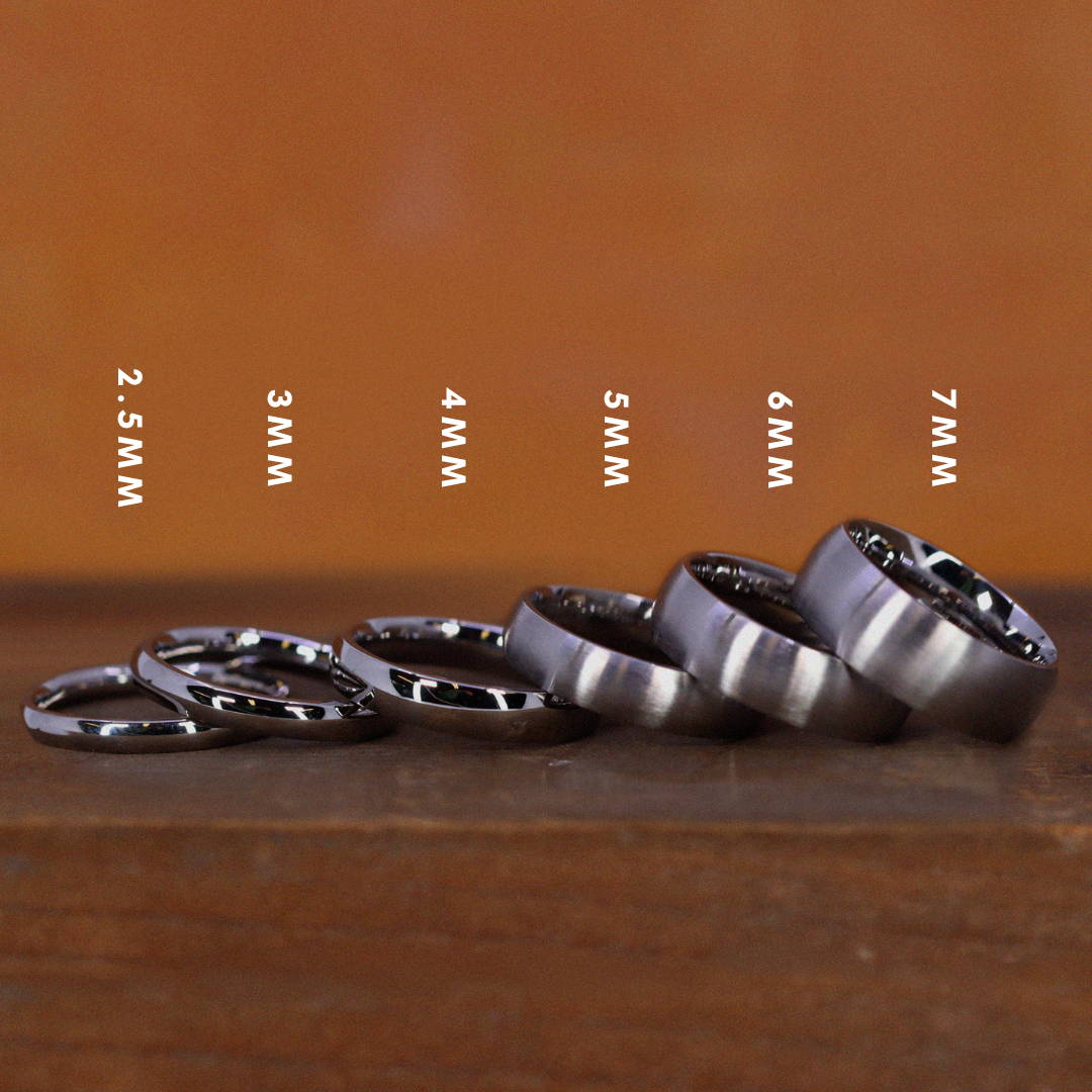 A line of stainless steel wedding rings placed on top of each other in increasing ring width.