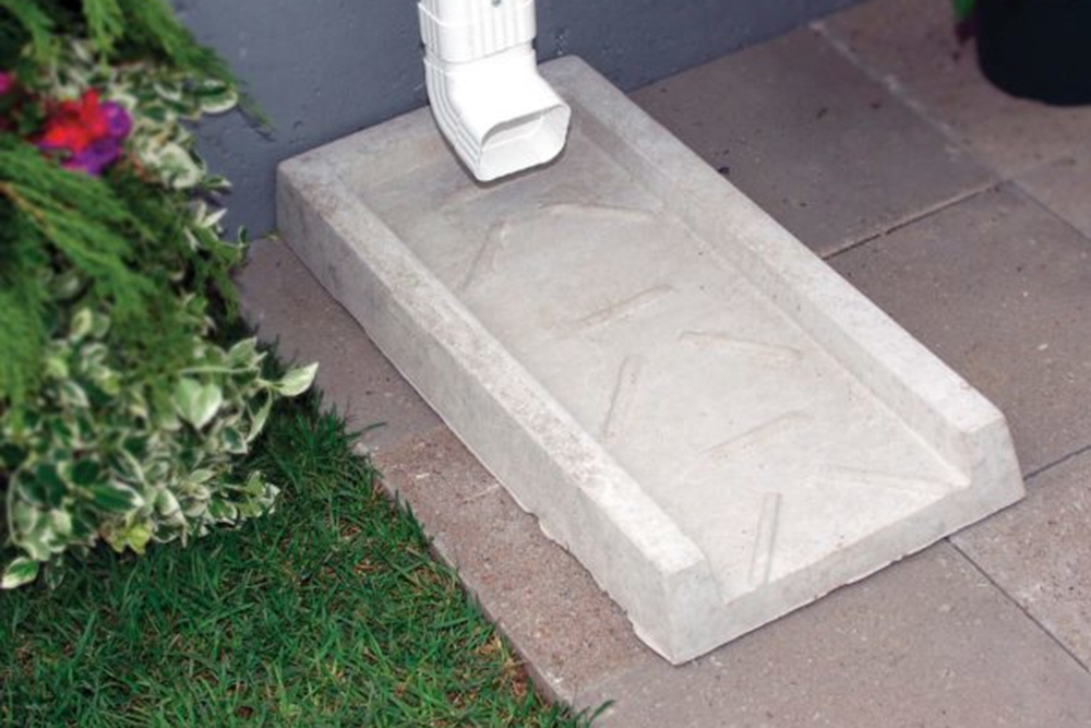 Downspout leading down to a Concrete Splash Pad on a patio.
