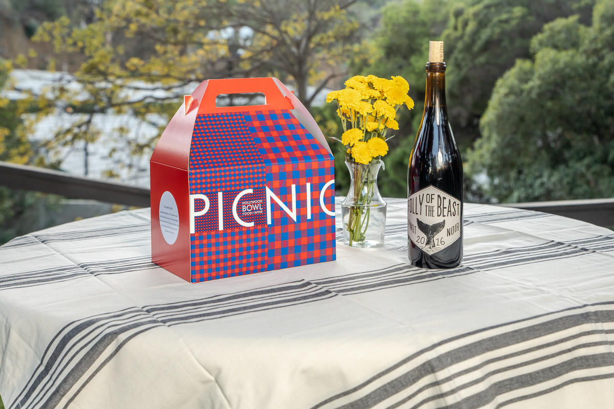 Una encantadora caja de picnic preordenada por Food + Wine con una botella de vino