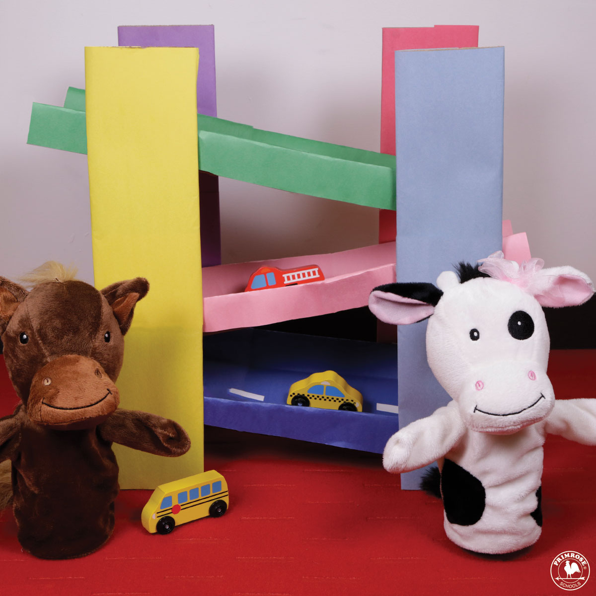 Primrose puppets Peanut the Pony and Molly the cow stand next to a homemade racetrack