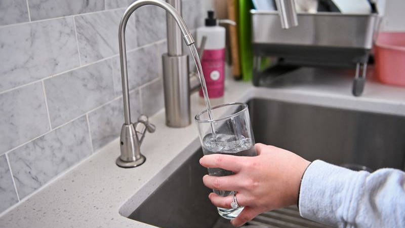 A person getting a glass of water from the sink.