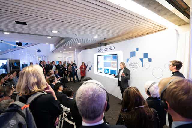 Speaker presenting at the World Economic Forum Science Hub, addressing a diverse audience in a modern conference space.