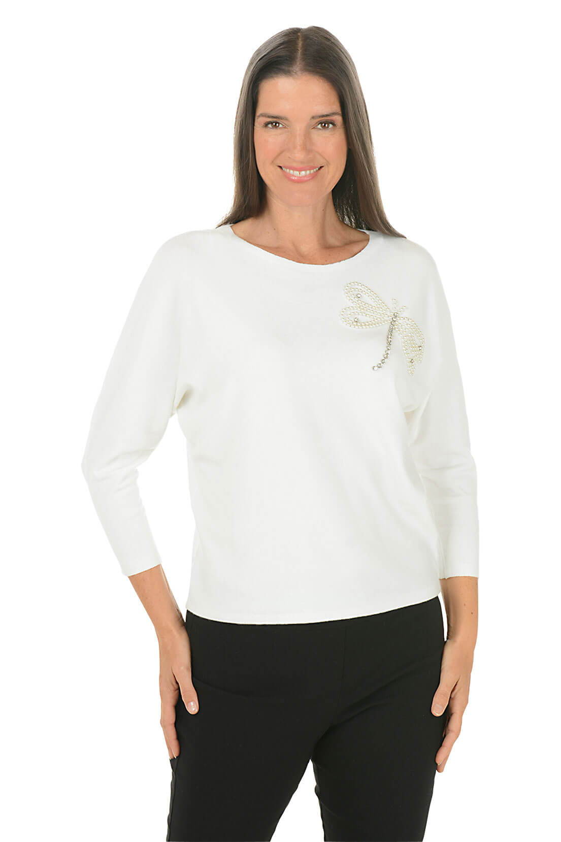 A woman wears a white sweater with a dragonfly embellishment