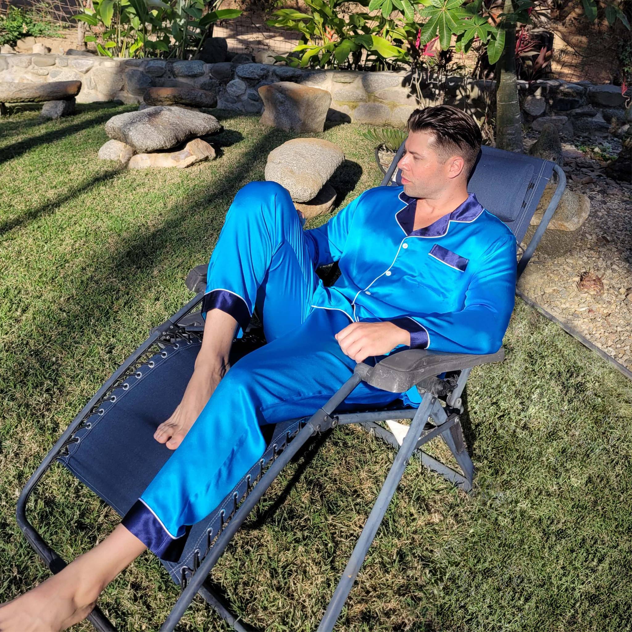 man lounging outside sitting in a reclining lawn chair and wearing a blue silk pajama set