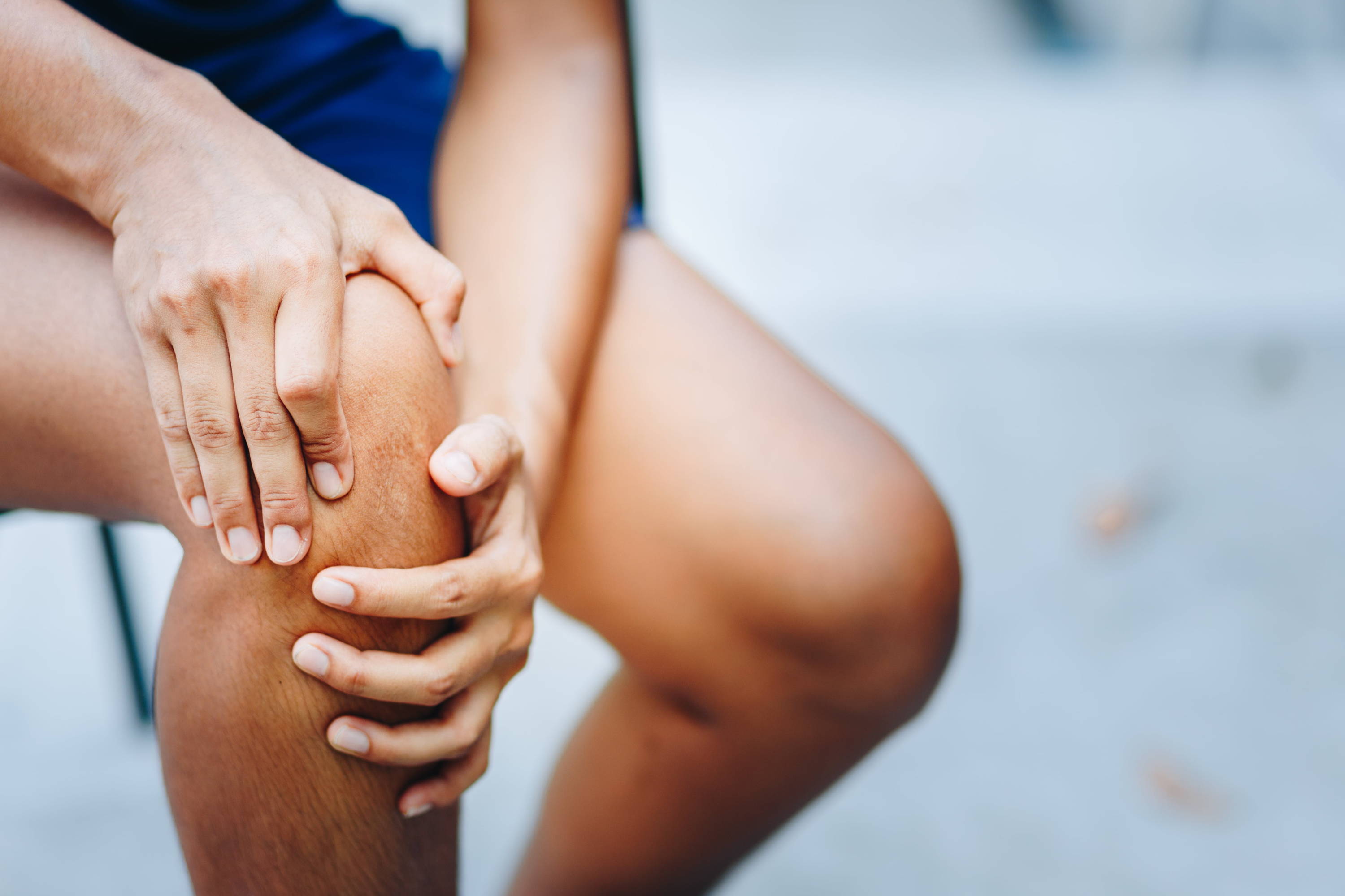 man sitting and holding his knee in pain