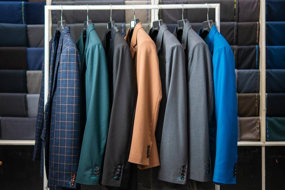 collection of seven suits in a variety of colors on a rack