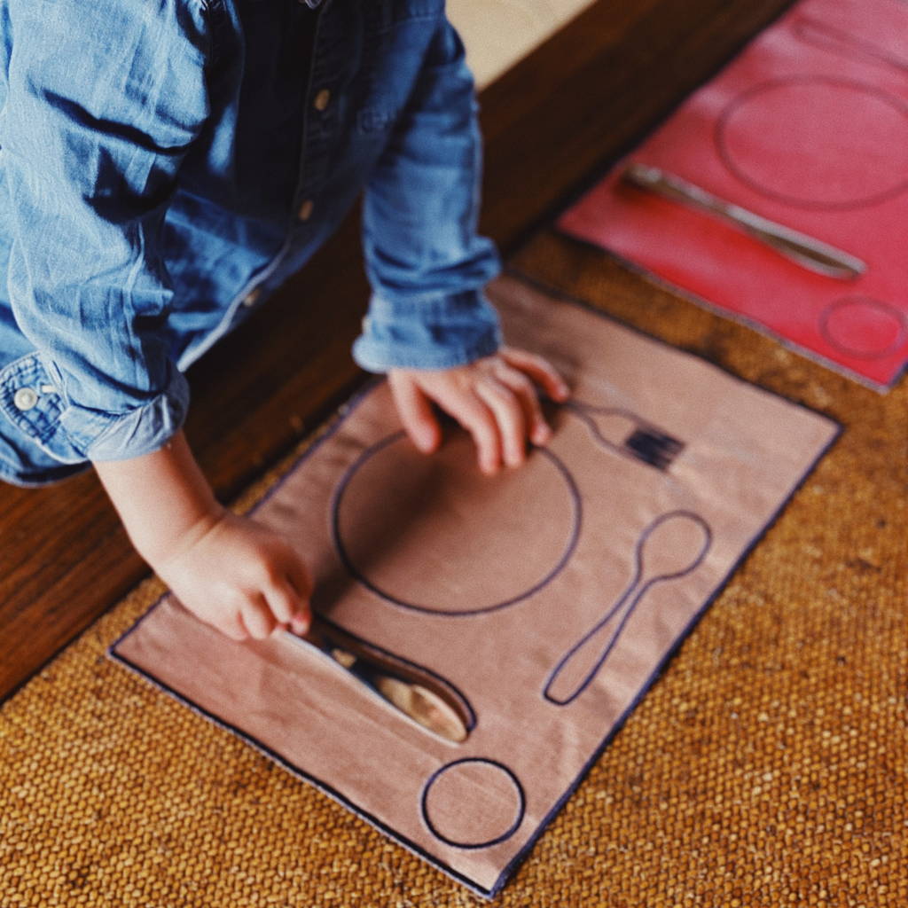 Un petit garçon utilise des couverts enfant pour dresser le couvert