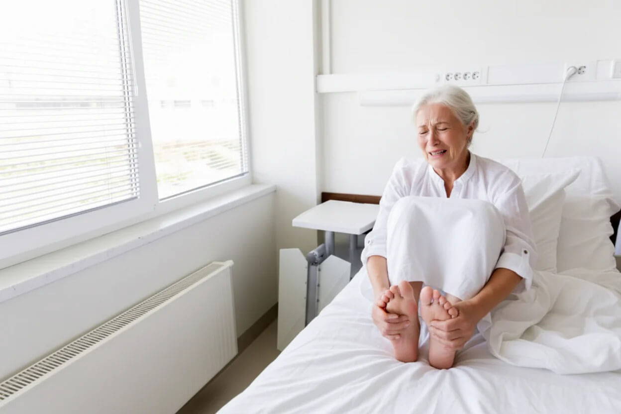 Oudere vrouw met pijnlijke voeten op bed
