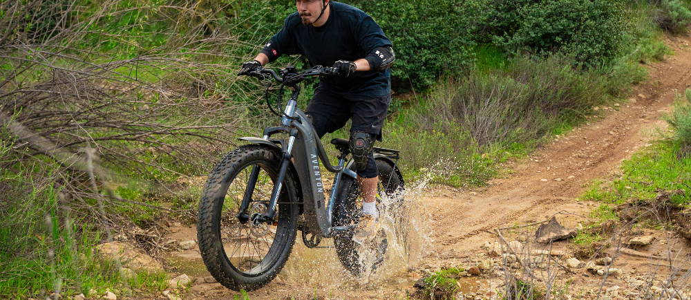 Mountain biker riding an e-MTB through a puddle